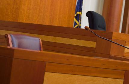Empty wooden judge's bench in courtroom with judge's chair and gavels, representing law and justice system.