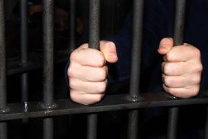 Man-behind-jail-bars-reaching