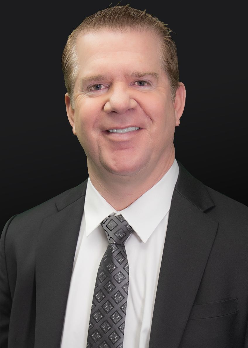 Professional headshot of a middle-aged man in business attire wearing a dark suit, white dress shirt, and patterned tie.