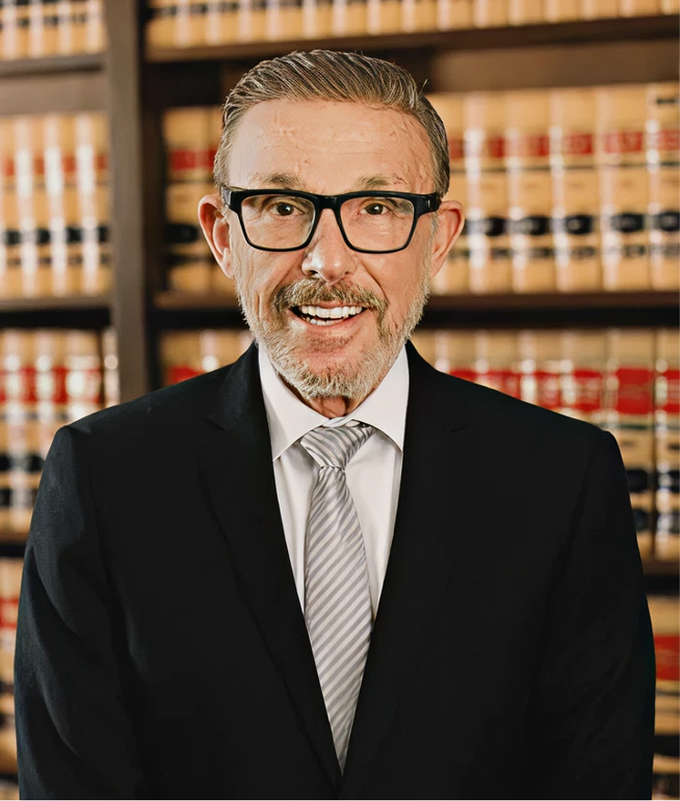 Professional lawyer in glasses smiling in front of law library shelves with legal books