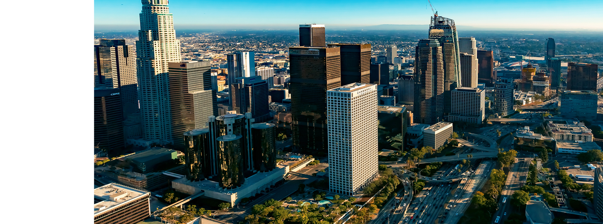 Aerial view of downtown Chicago skyline with tall skyscrapers, highways, and green spaces under clear blue sky