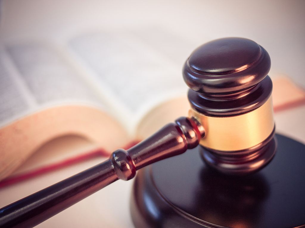 Judge's gavel with law book in background symbolizing justice, legal authority, and court proceedings.